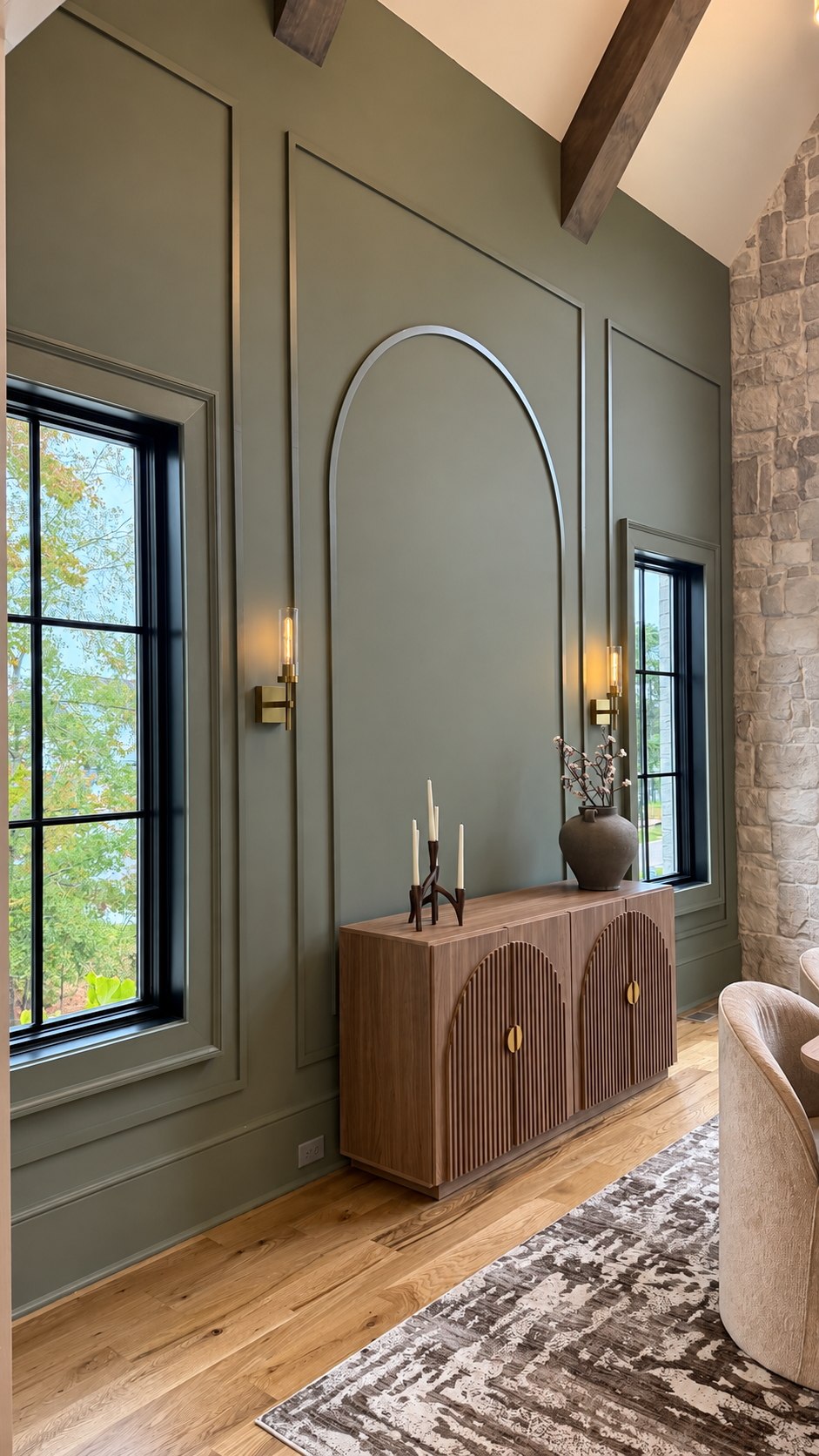 Dining-room sideboard between tall windows and brass sconces