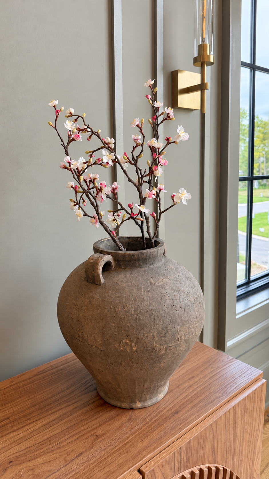 Ceramic vase with flowering branches on the dining sideboard