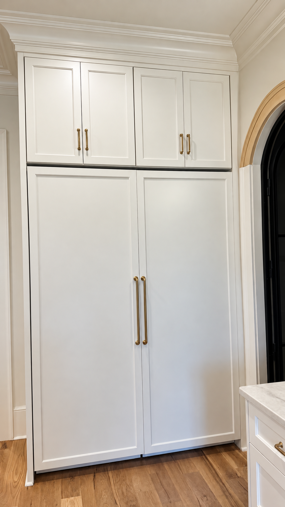 Paneled Monogram refrigerator beside the arched wine-cellar entrance