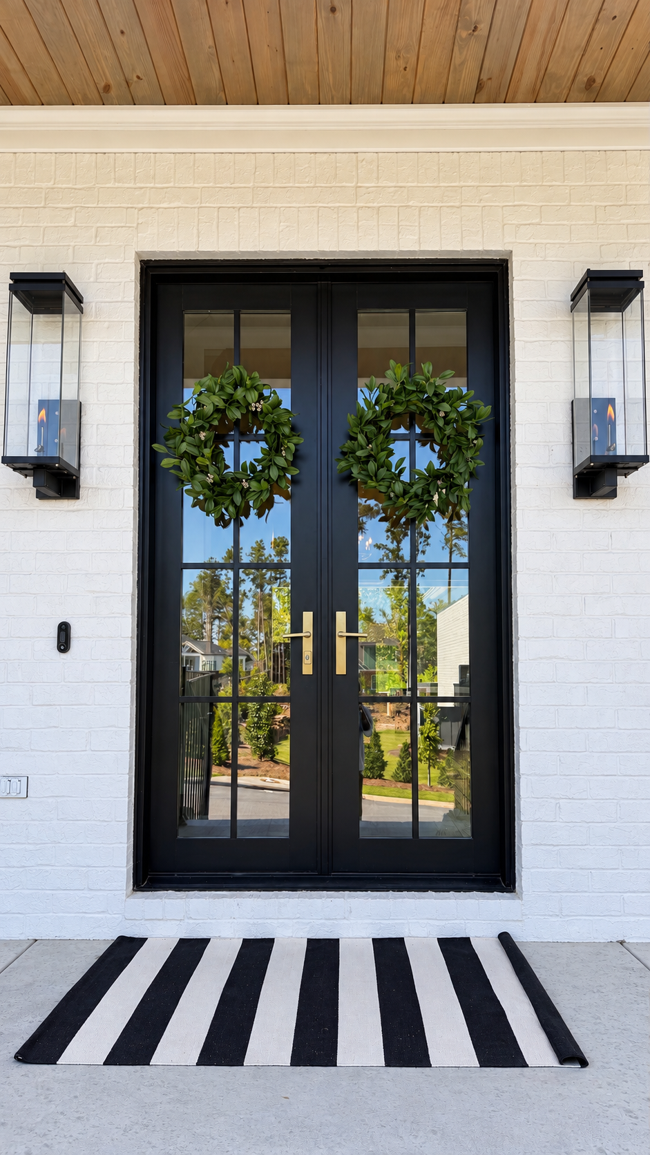 Black double front doors with wreaths and lanterns