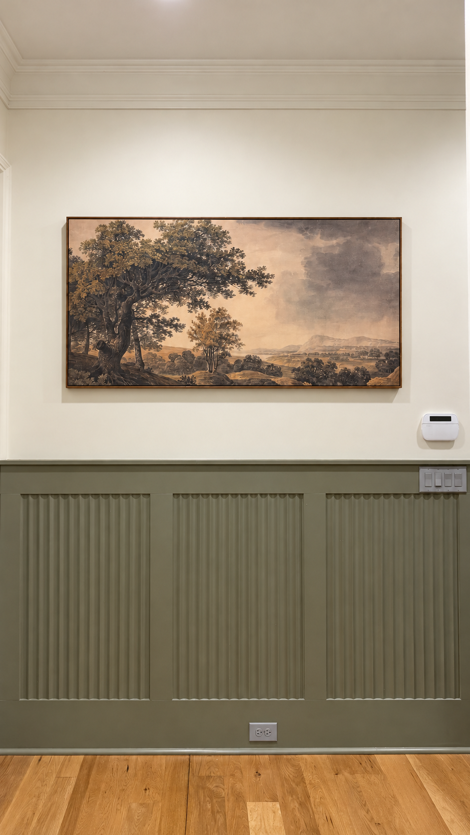 Framed landscape artwork above olive fluted wall molding